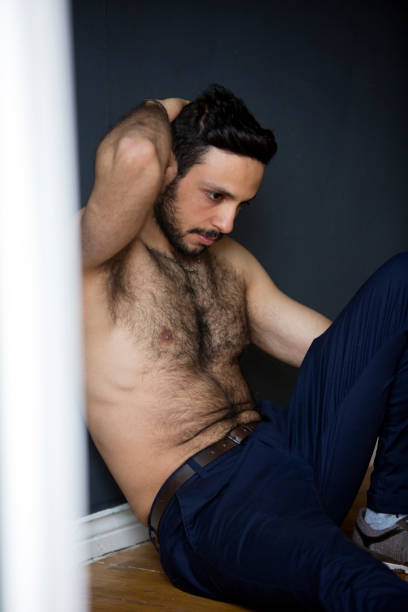istock handsome young man sitting shirtless on floor 697026724