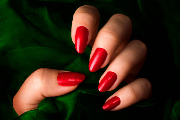 red nails Female hand with red nails is holding green fabric. red nail polish stock pictures, royalty-free photos & images