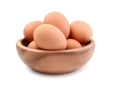Chicken eggs in a wooden bowl isolated on white