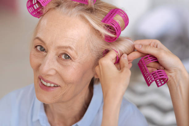 istock Senior woman getting help with hair rollers 697031358