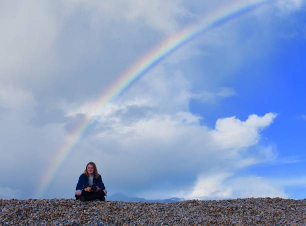 istock Rainbow over Beach with girl sitting below 697034538