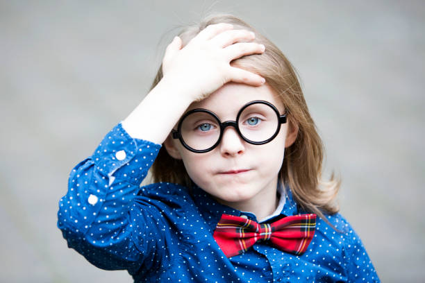 istock blond boy with bow tie and big glasses looking upset 697034570