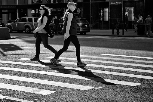 New York City, USA - October 15, 2016: Urban life scene. Two female pedestrians are seen passing each other in the crosswalk along Broadway, Upper West Side of Manhattan.