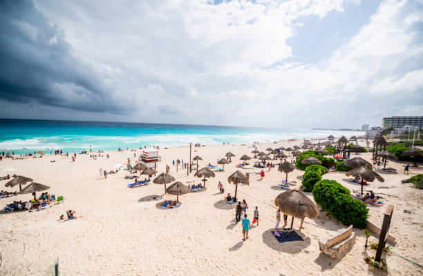 praia lotada de cancun - cloud sea beach umbrella sky - fotografias e filmes do acervo