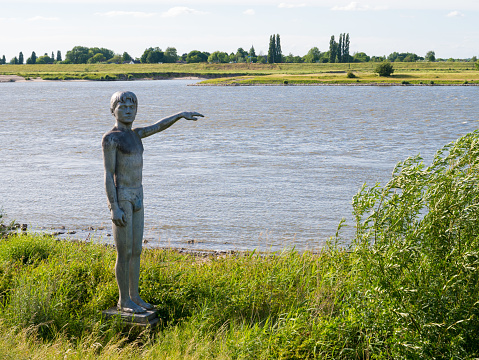Statue of waterboy on south bank of Waal river near Waalkade in fortified town of Zaltbommel, Gelderland, Netherlands