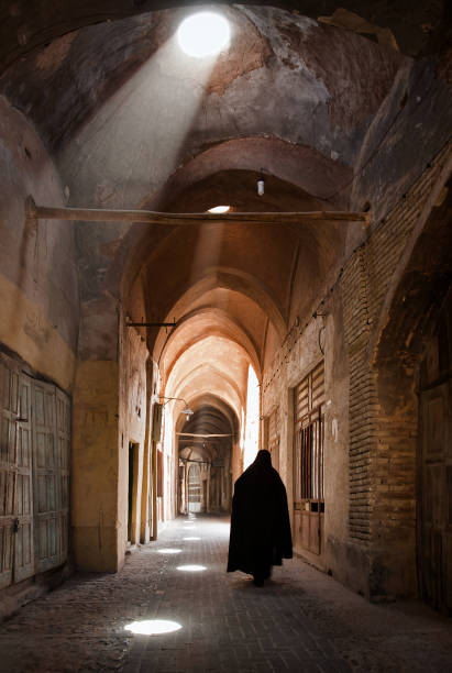Woman in Veil Passing through Grand Old Bazaar of Yazd stock photo