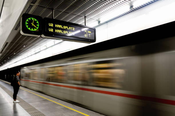 Vienna, Austria - May 17, 2017: Subway underground station in Vienna (Austria) with a train running beside the platform, with a passenger waiting for it, on may 17, 2017