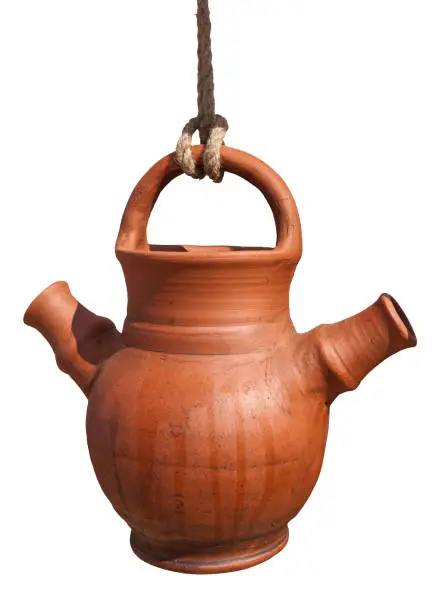 Ancient water pot with two beaks or spouts hangs on a rope. Isolated against white background.