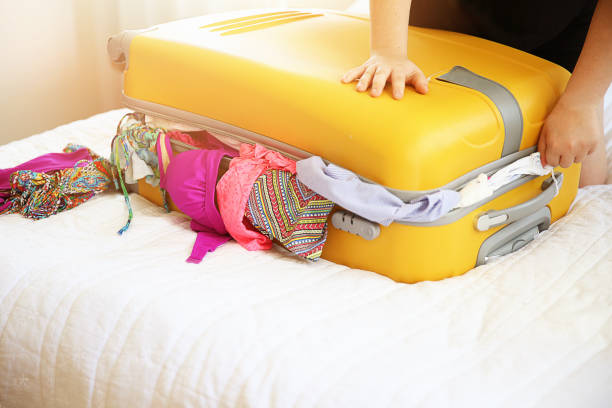 istock Woman trying to close overfilled suitcase 697093906