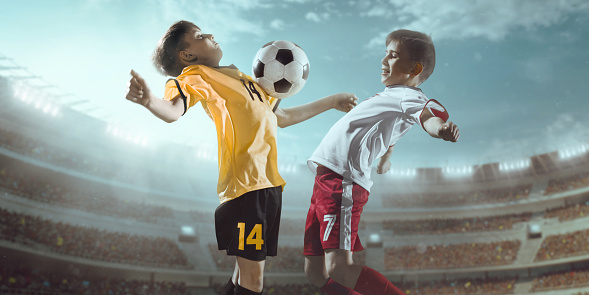 Soccer kids players in action in 3D stadium. They are dressed in a professional football uniform. Behind the players is a stadium with fans in the stands.