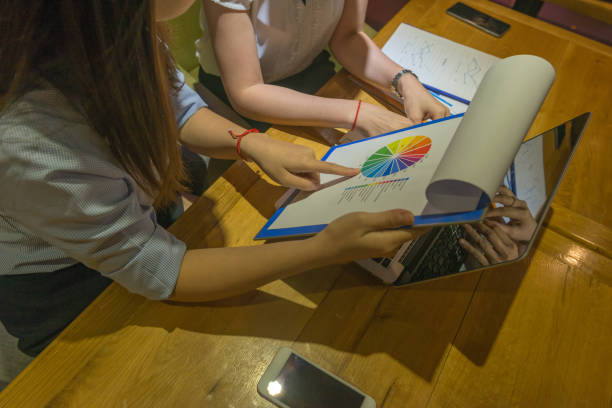 istock Women working late together, reading report, teamwork 697137910