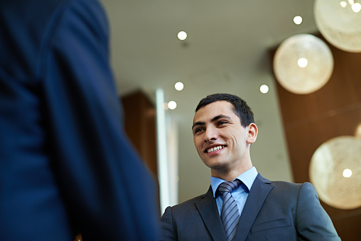 Smiling handsome young businessman talking to colleague during conference break