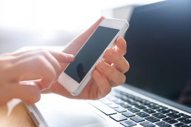 istock Hands using phone in front of computer, home work place, day time with sun fare 697207624