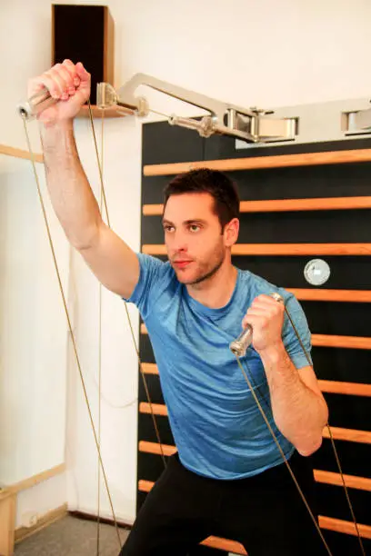 Athletic handsome man working fitness sport exercise for the chest and hands in sports center. Kinesis technology machine straps in the gym. Sport, fitness, healthy lifestyle, people gym concept.