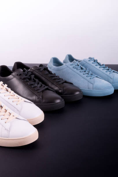 istock Three pair of sneakers on black background. Black, white and blue shoe. 697217814