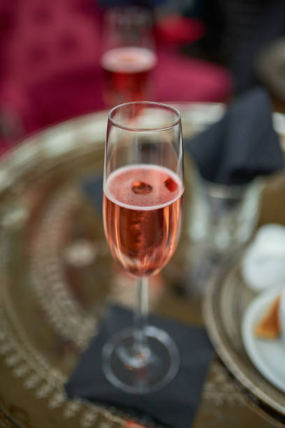 Flute of sparkling rose champagne on a table Flute of romantic sparkling rose champagne on a table in a restaurant viewed close up high angle with focus to the beverage rose champagne stock pictures, royalty-free photos & images