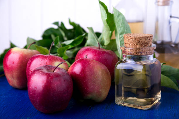 istock Apple cider vinegar. Three glass bottle on blue background. Red apples. 697231772