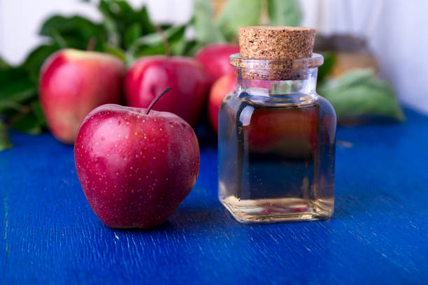 istock Apple cider vinegar. One glass bottle on blue background. Red apples. 697231774