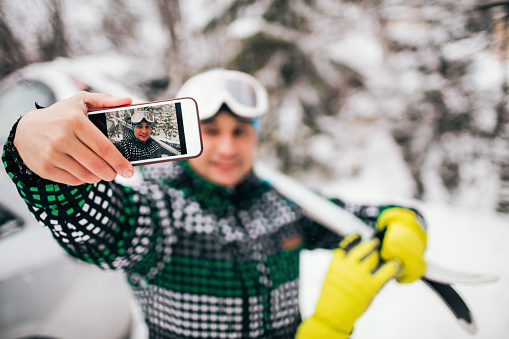 Smiling skier making a selfie after good skiing day