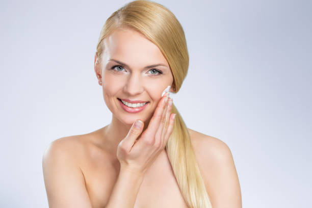 istock Young pretty woman applying cream on face 697235648