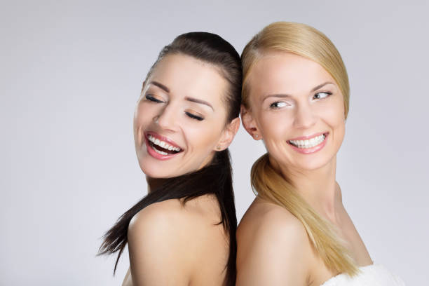 istock Two pretty women leaning on each other back laughing 697236182