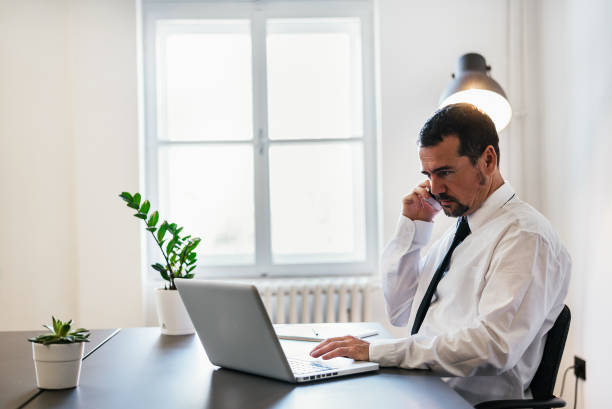 istock Businessman talking over the phone while typing on laptop at same time. 697238978