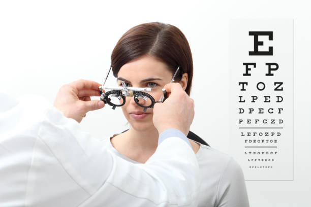 mujer haciendo medición de vista con marco de ensayo y prueba visual gráfico en blanco - looking eyesight optometrist focus fotografías e imágenes de stock