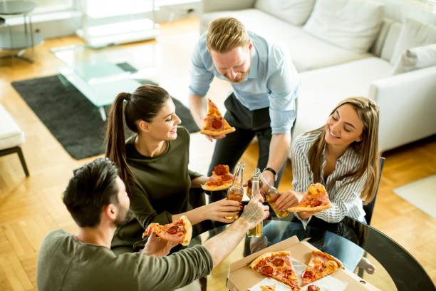 istock Young people eating pizza and drinking cider in the room 697252478