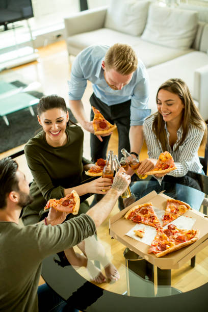 istock Young people eating pizza and drinking cider in the modern interior 697255736