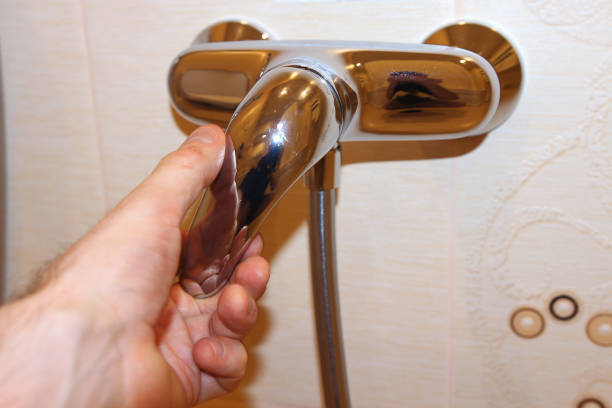 istock hand opens shower faucet in the bathroom macro. 697257090