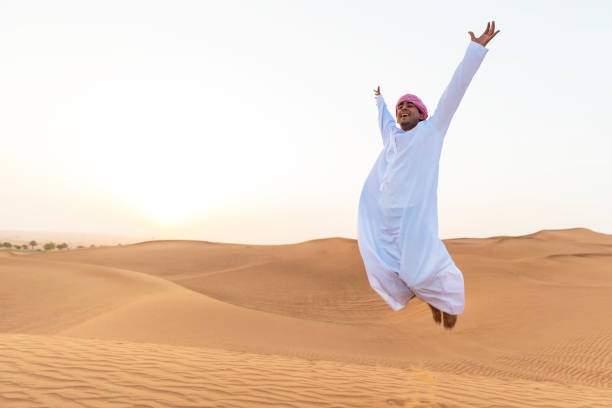 Young Arab jumping on the sand dunes