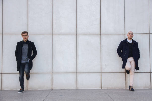 istock Two young entrepreneurs leaning against a white wall. 697273886