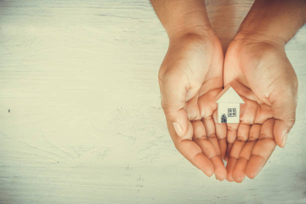 istock Hands holding little wooden house  model 697277492