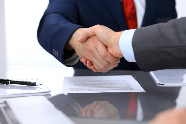 istock Two business man shaking hands to each other above signed contract 697288522