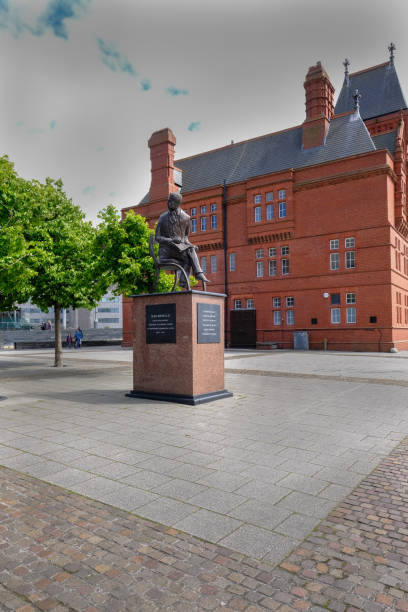 Cardiff Bay, Wales - May 20, 2017:  Ivor Novello statue Pierhead building and statue of Ivor Novello in front.  A vertical shot to show the statue in its setting. national assembly for wales stock pictures, royalty-free photos & images