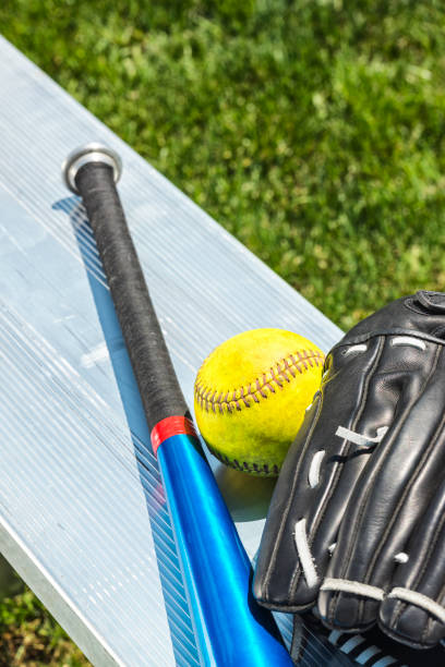 yellow softball, glove and aluminum bat on park bench - softball playing field fluorescent team sport imagens e fotografias de stock