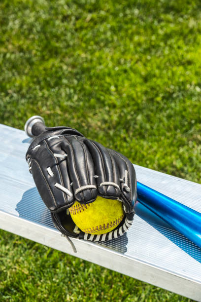 yellow softball, glove and aluminum bat on park bench - softball playing field fluorescent team sport imagens e fotografias de stock