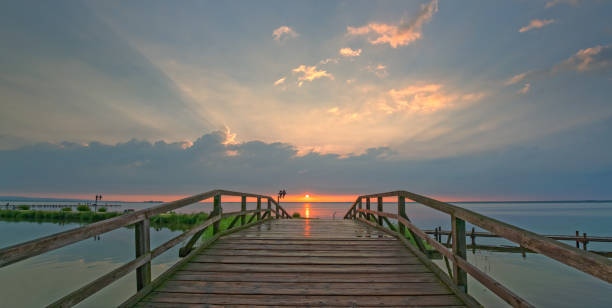 istock Sunset over bridge at lake with majestic cloudscape 697302842