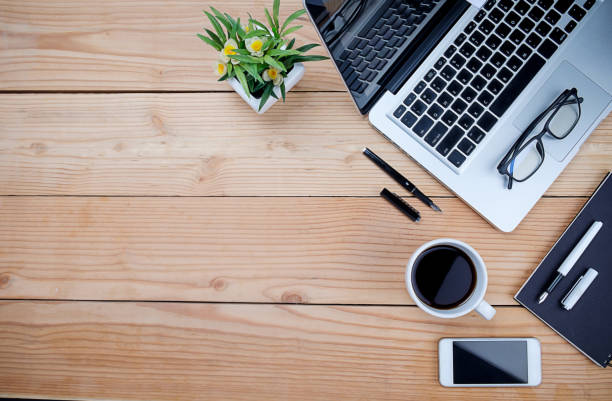 istock Office desk table with pen, keyboard on notebook, cup of coffee and flower. Top view with copy space (selective focus). 697315542