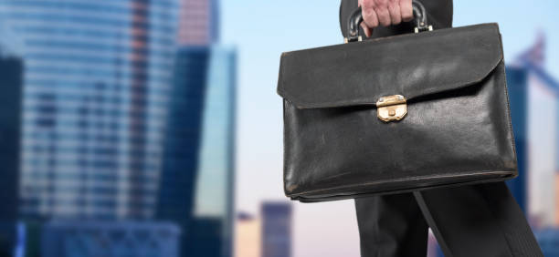 istock Businessman holding a briefcase with office buildings in background 697322488