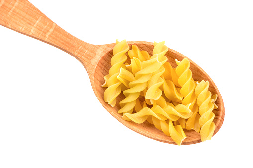 Pasta fusilli in a wooden spoon on white background, closeup