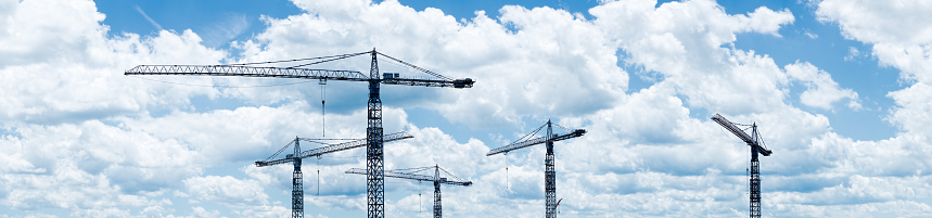 Cranes and scattered clouds dominate the skyline in this panoramic image.