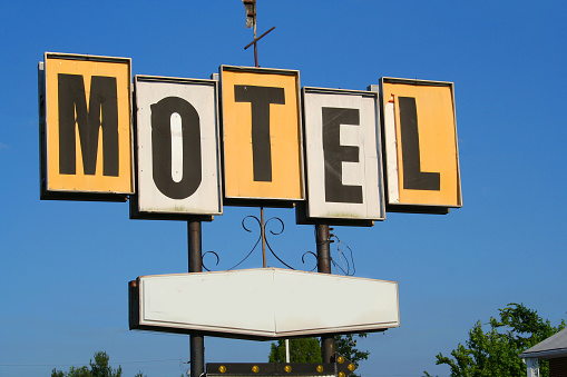 A vintage motel sign against a blue sky.