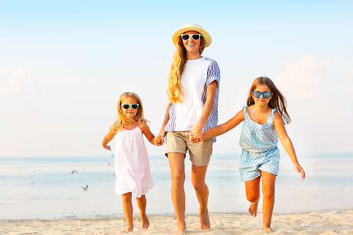 Happy young family having fun running on beach at sunset. Family traveling concept