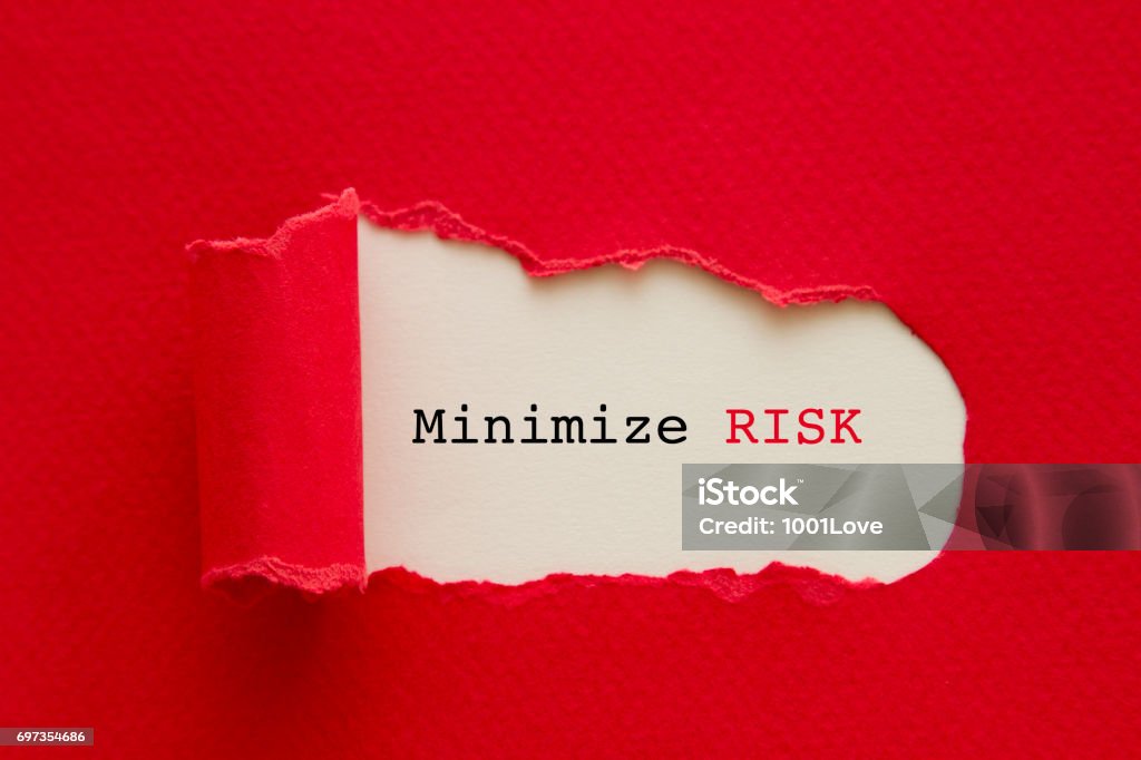 MINIMIZE RISK MINIMIZE RISK written under torn paper. Risk Stock Photo