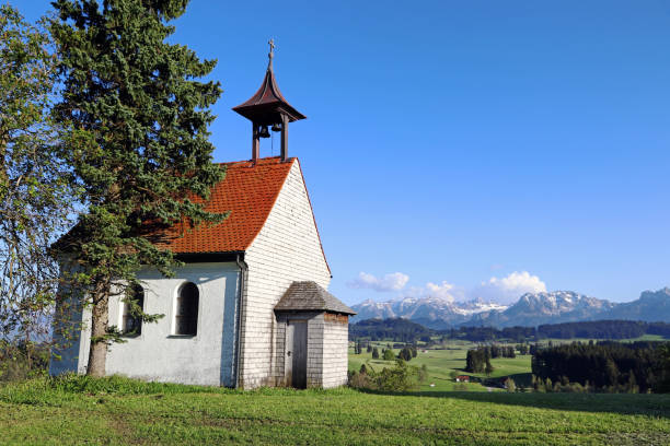 A small white chapel in front of the Allgaeu Alps