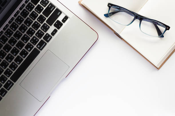 istock Top view of workspace, computer laptop, notebook and eyeglasses, on the white desk background 697358432