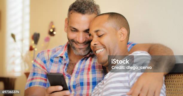 Happy Gay Couple Looking At Pictures On Mobile Phone Stock Photo - Download Image Now