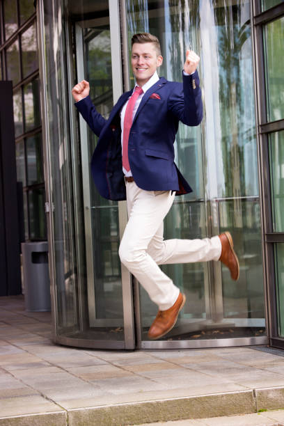 istock happy businessman jumping in front of office building 697366566