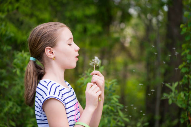 istock Happy little girl blowing dandelion 697369434
